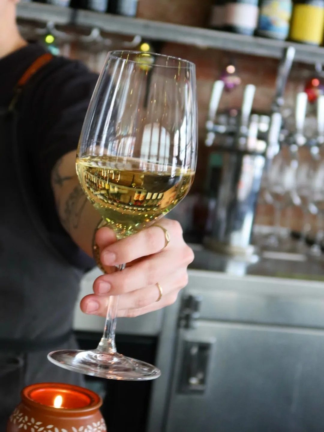 A glass of white wine held up at the bar
